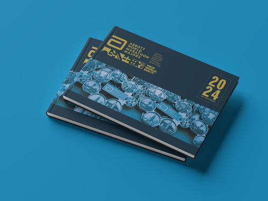 Stack of Abbott World Marathon Majors 2024 photo books with a blue and gold cover featuring race medal artwork and city names