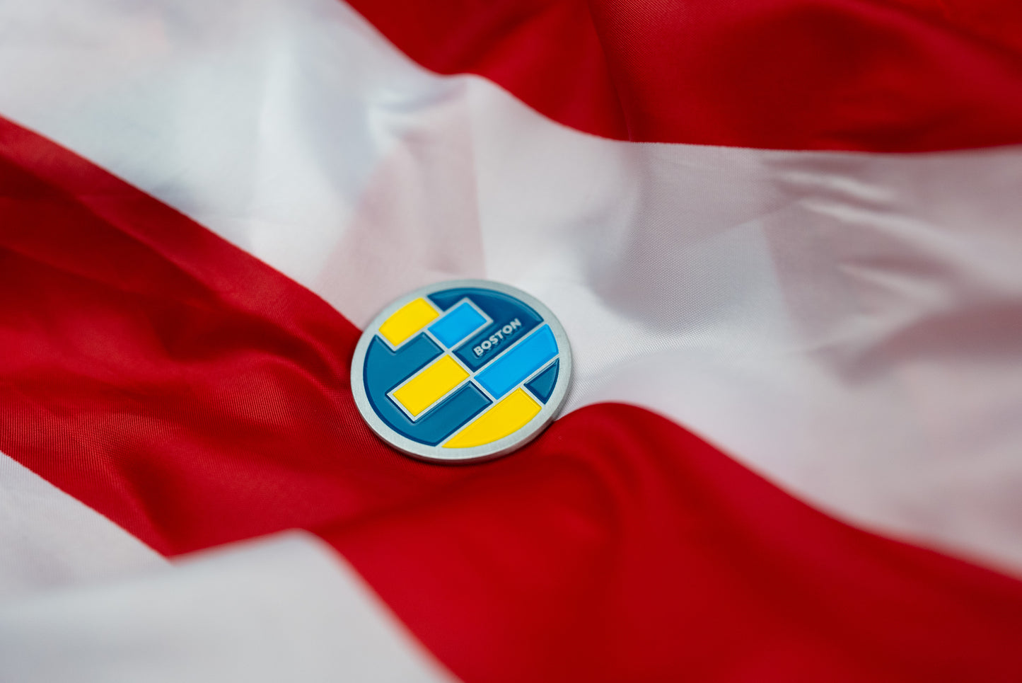 Abbott World Marathon Majors Boston collectible coin with blue and yellow geometric design on red and white fabric.