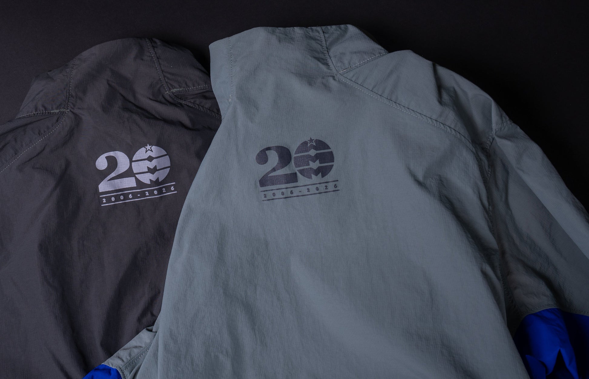 Two jackets, one gray and one black, with '20' logo on a dark background