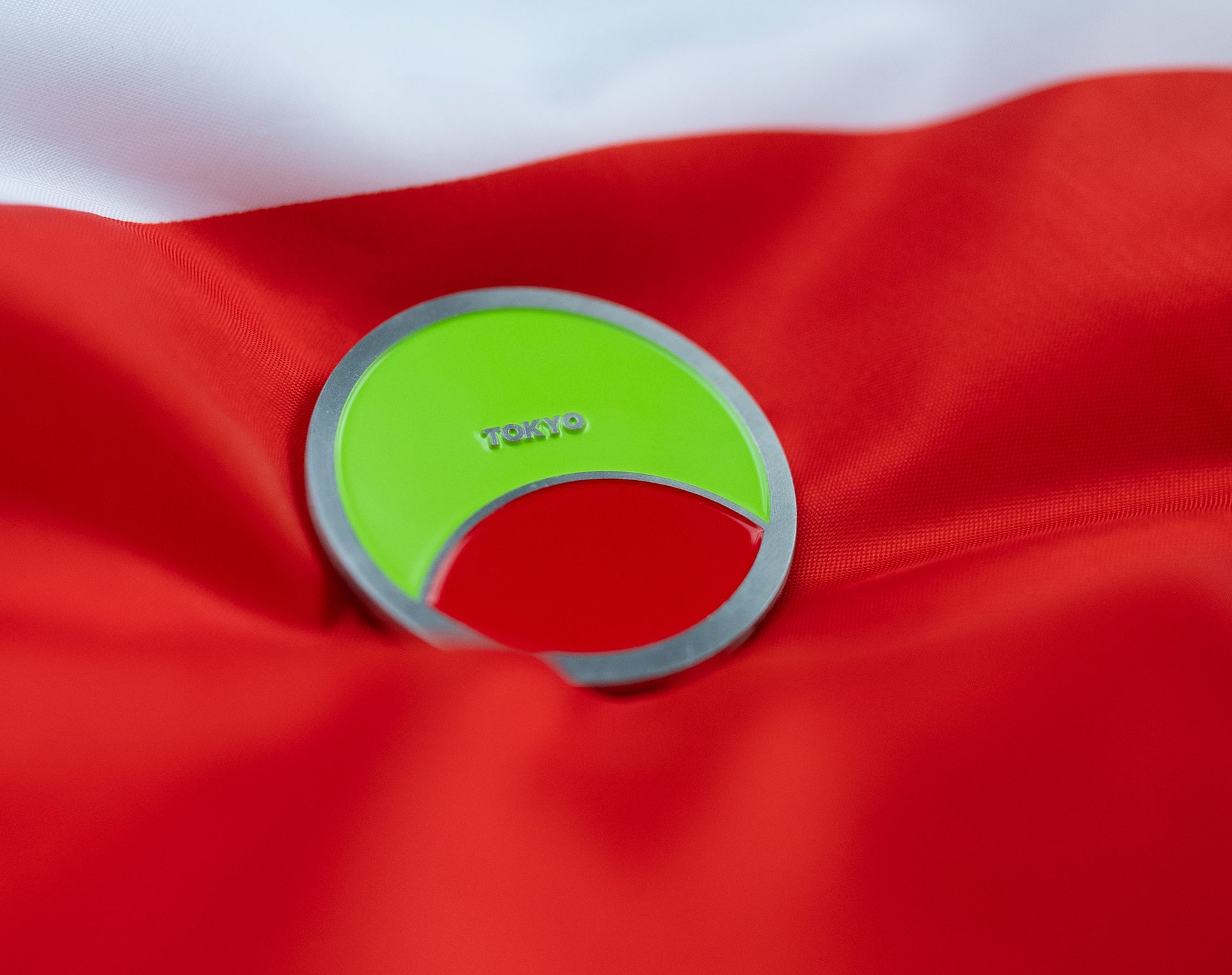 Abbott World Marathon Majors Tokyo collectible coin with bright green and coral colors displayed on red and white fabric.