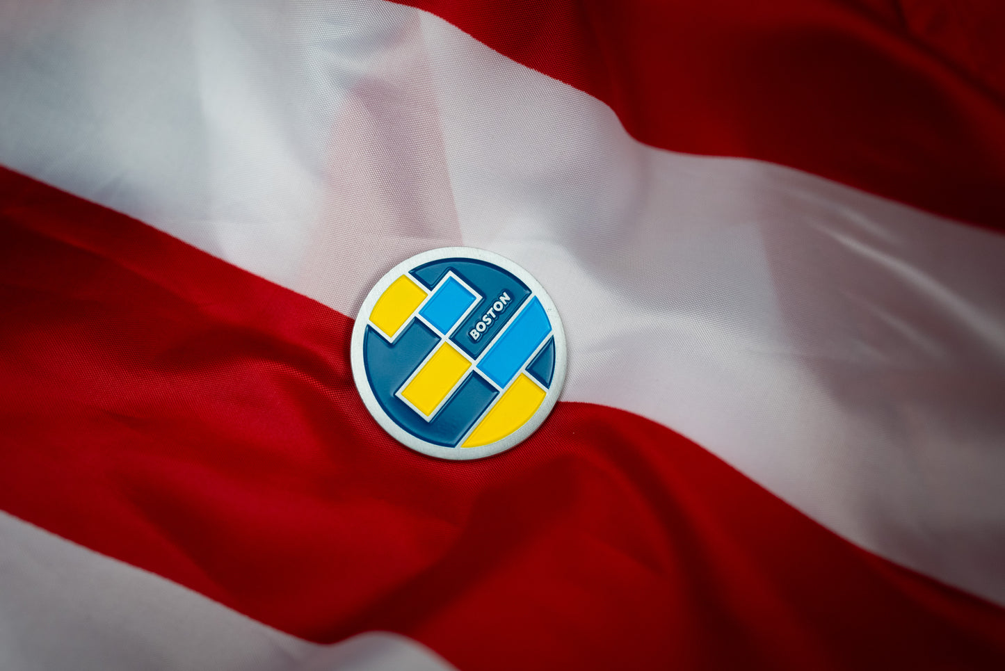 Abbott World Marathon Majors Boston collectible coin with blue and yellow geometric design on red and white fabric.