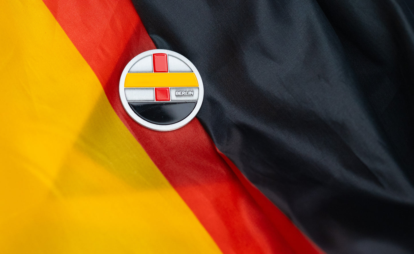 Abbott World Marathon Majors Berlin collectible coin with red, yellow, and black geometric design displayed on a German flag background.