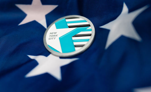 Abbott World Marathon Majors New York City collectible coin with teal and black design resting on blue star-patterned fabric.