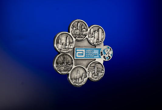 Abbott World Marathon Majors Six Star pin badge featuring raised city skyline icons for Tokyo, Boston, London, Berlin, Chicago, and New York, shown on a blue gradient background