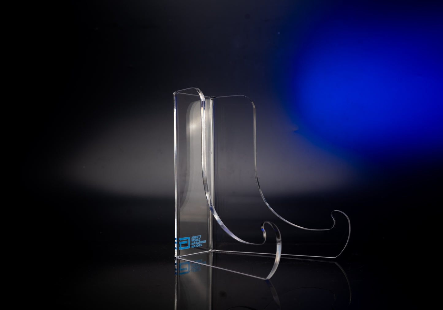 Clear acrylic display stand with curved supports, featuring the Abbott World Marathon Majors logo, shown against a dark background with blue lighting.